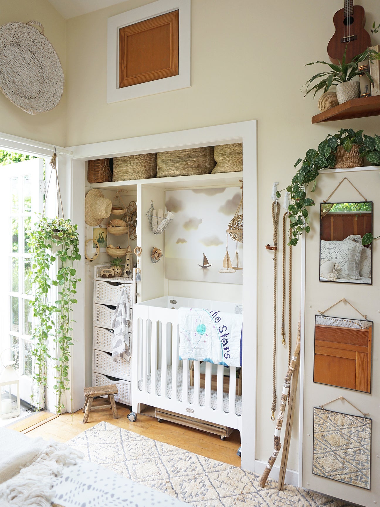 a crib and dresser inside of a closet with lots of plants and mirrors around it