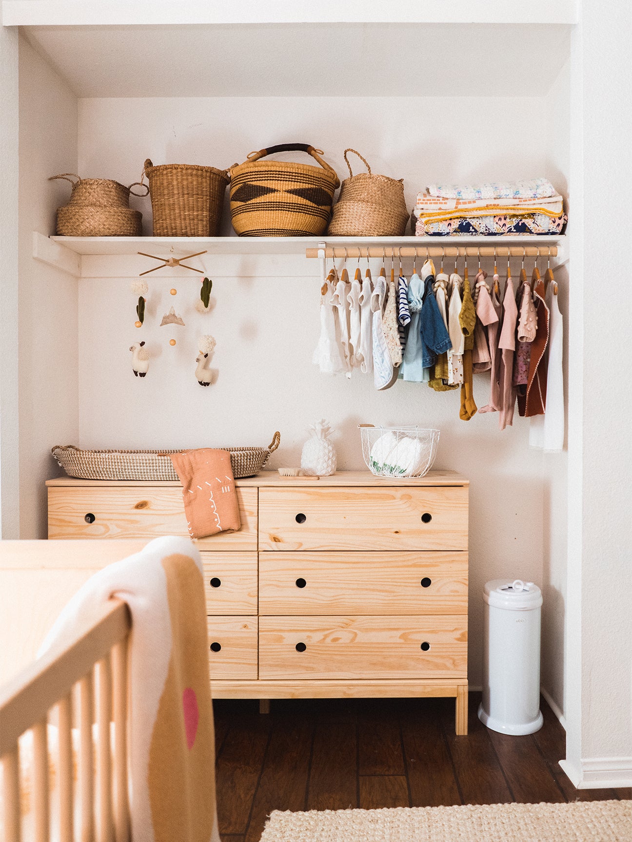changing table in an aclove witha shelf of clohtes above