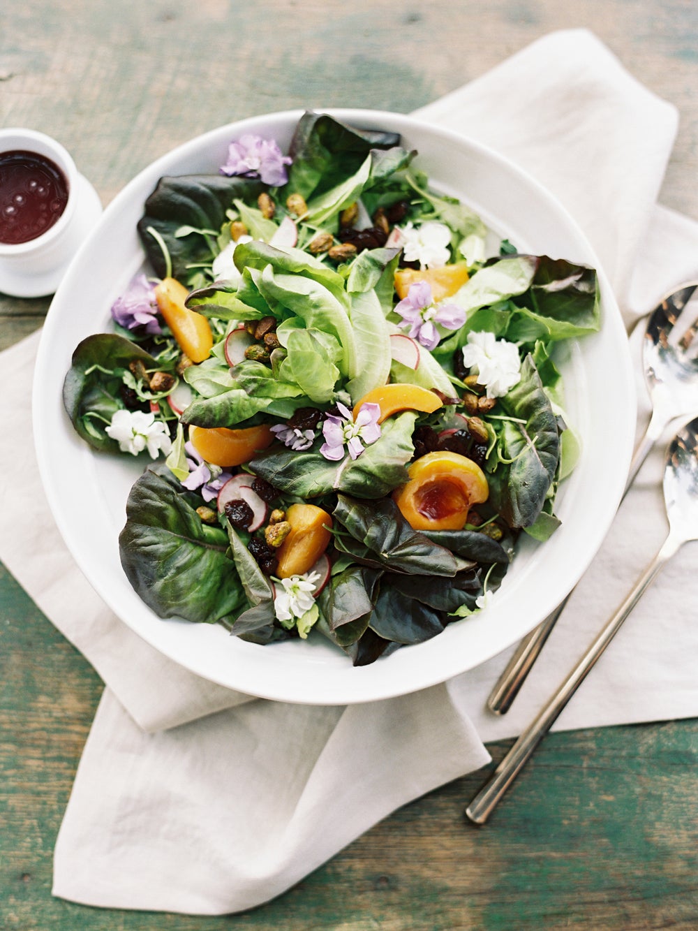 white bowl with salad of dark greens, oranges, lilac flowers