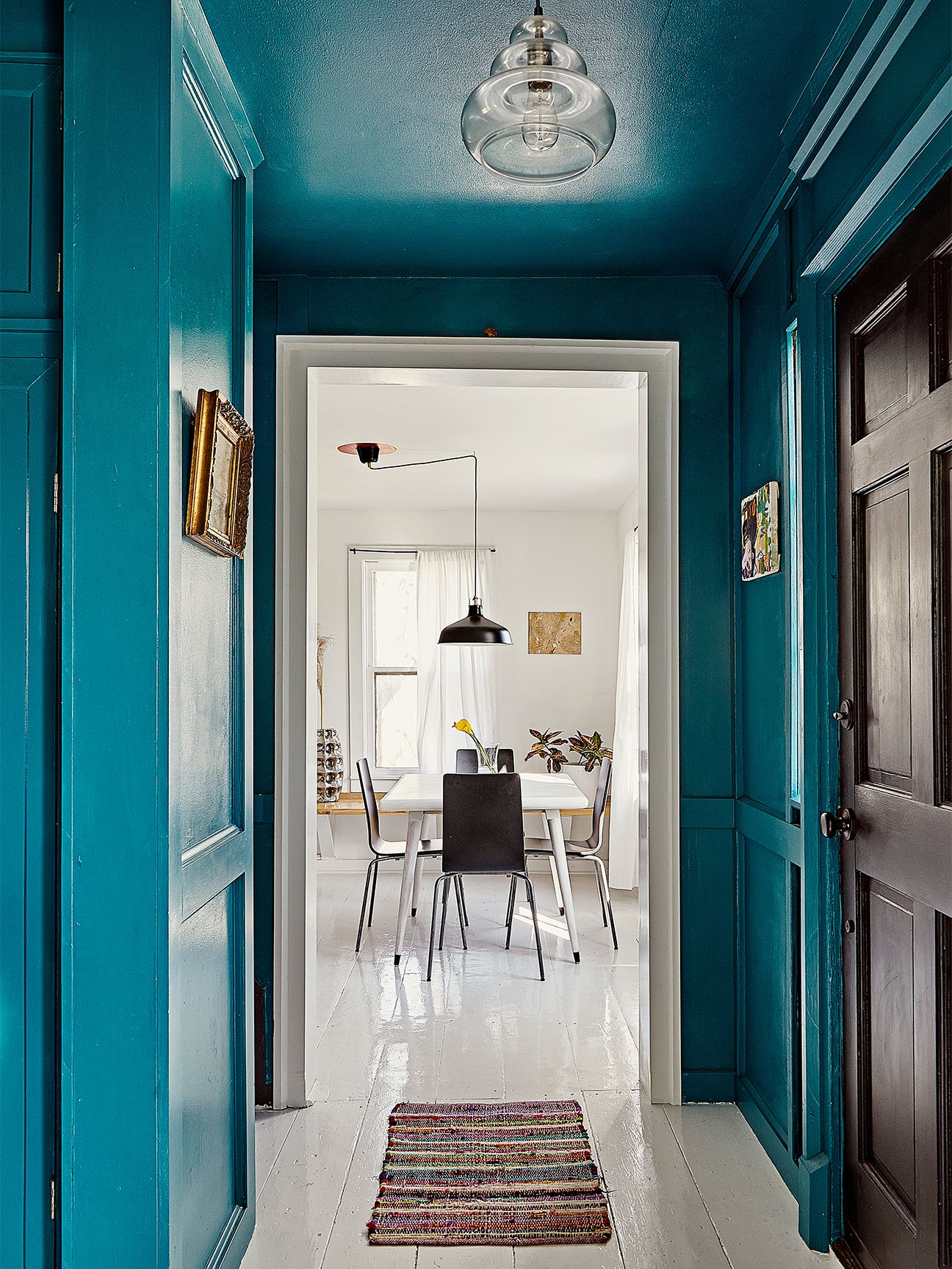 blue hallway leading to an all white dining room