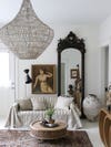 white living room with striped gray sofa and large antique mirror