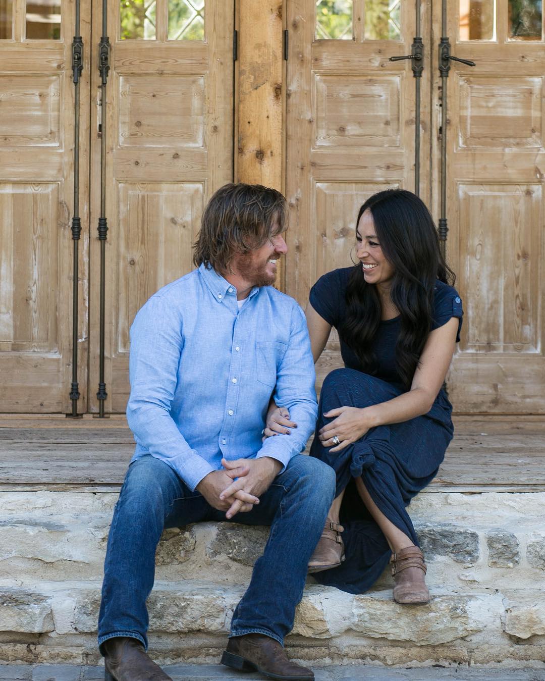 chip and joanna gaines sitting on steps looking at each other