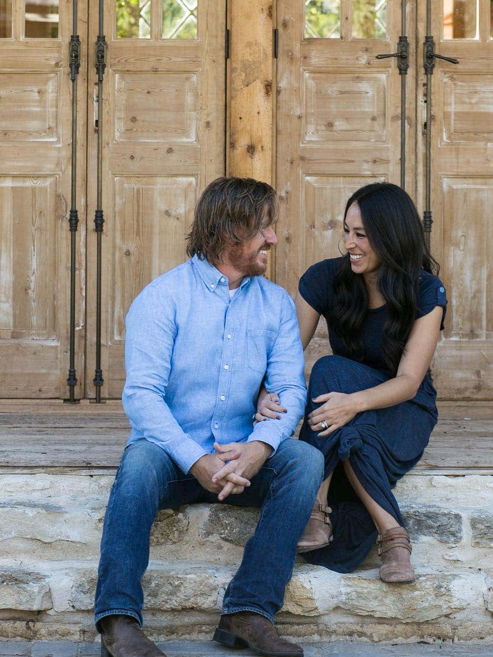 chip and joanna gaines sitting on steps looking at each other