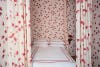 red floral drapery around a bed that matches the walls