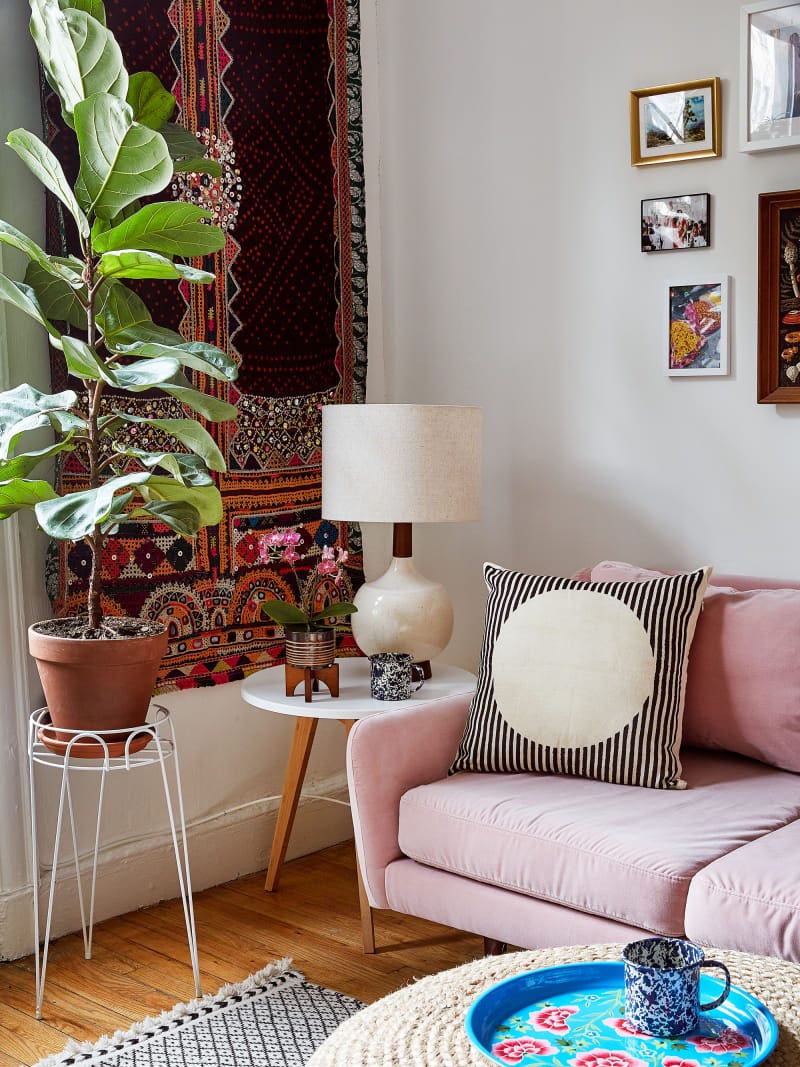 eclecitc living room with a fiddle leaf fig and pink sofa and tapestry wall