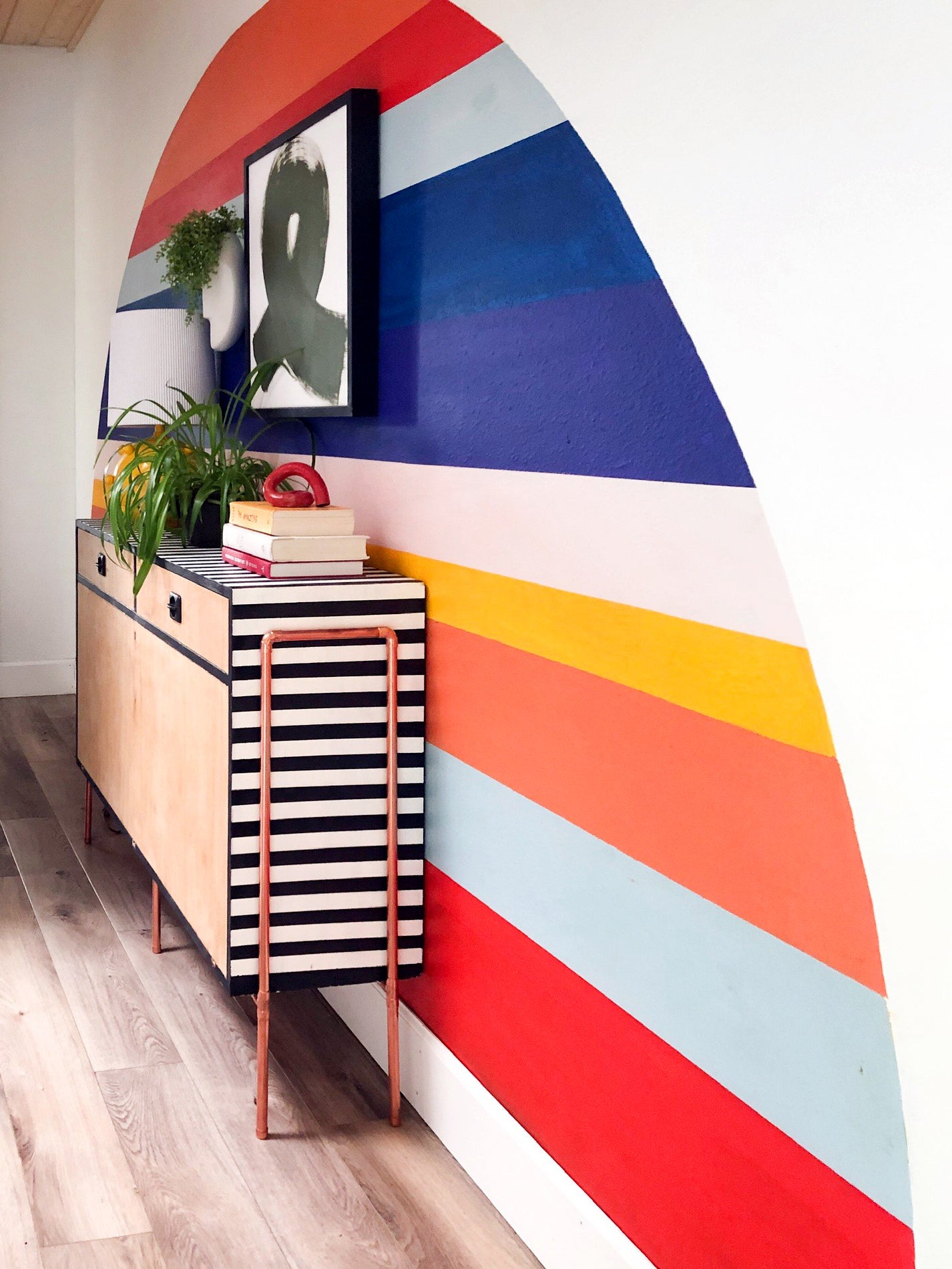 striped rainbow wall with a sleek credenza