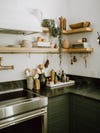 floating wood shelves with dark green kitchen with white hood