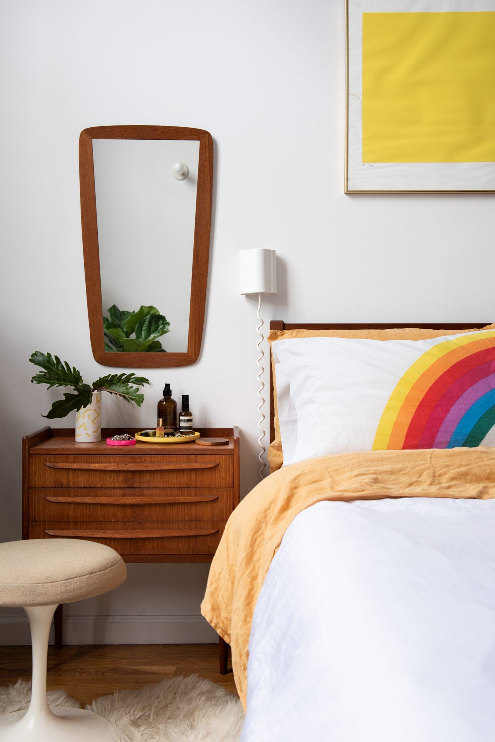 White bedroom with rainbow bedsheets and art