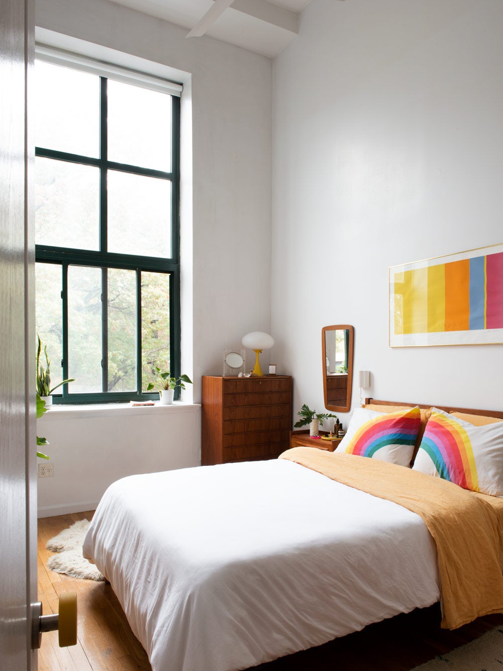 White bedroom with rainbow bedsheets and art