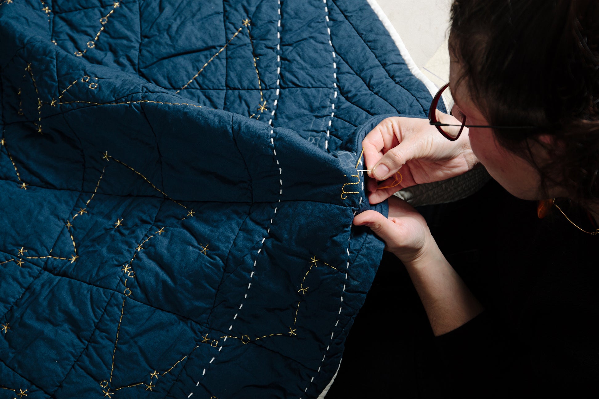woman stitchign a quilt