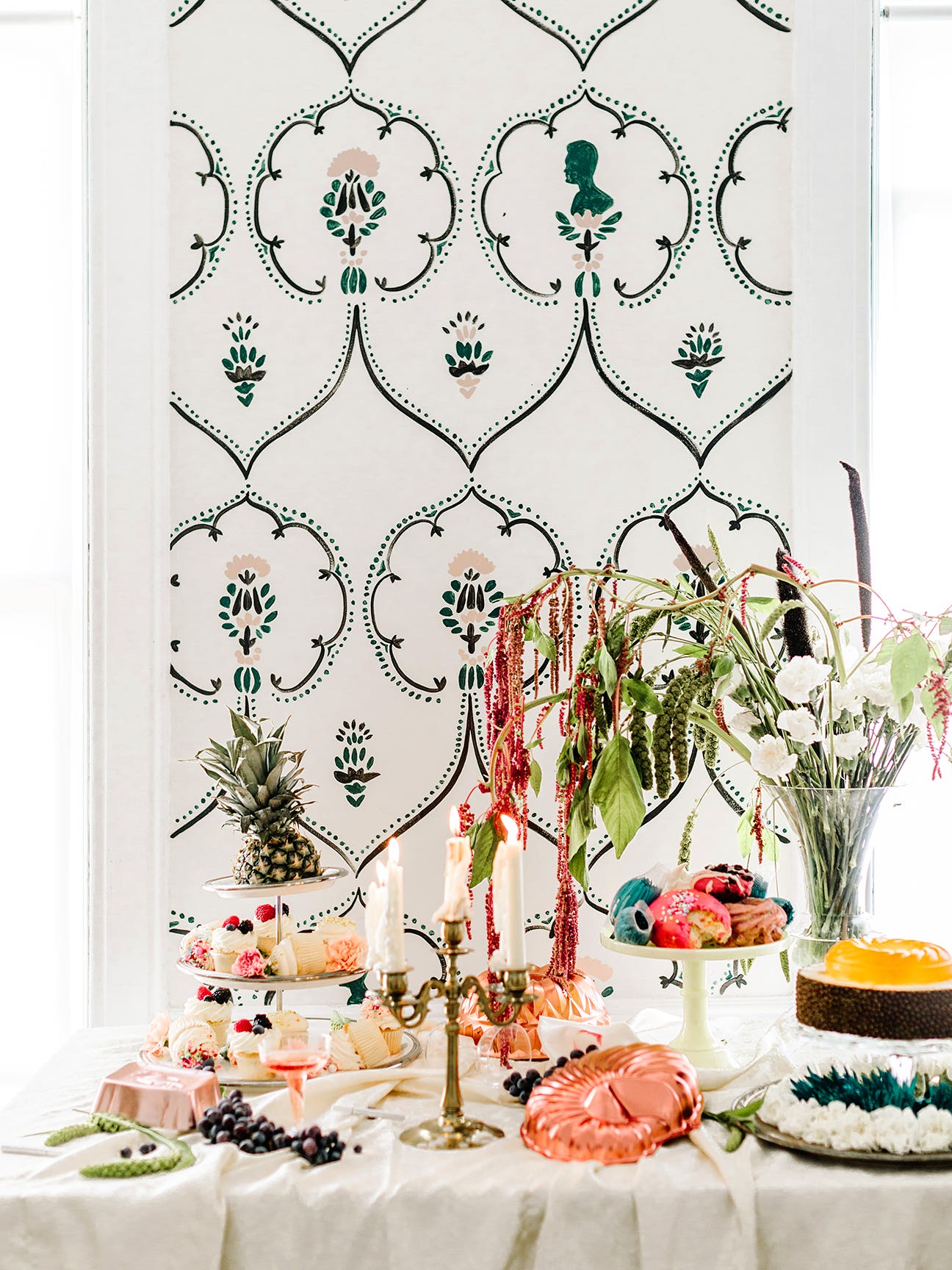 An elaborate tablescape in front of a wallpaper-covered wall.