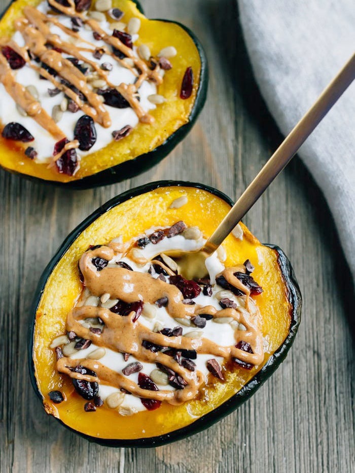 Two acorn squash halves filled with yogurt and assorted toppings.