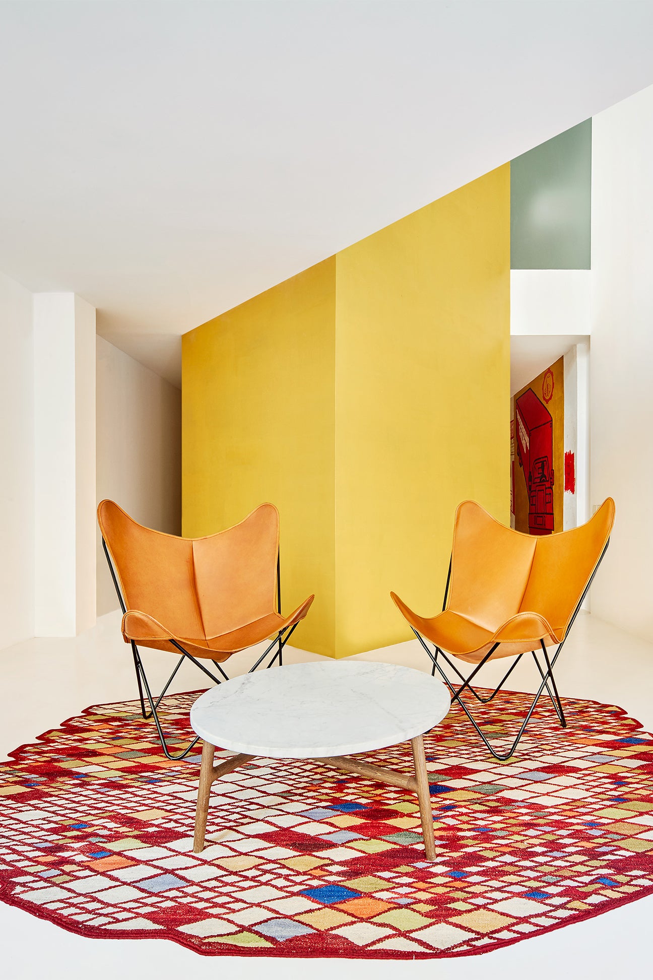 White room with yellow accent wall and butterfly chairs