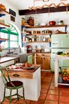 eclectic kitchen with green fridge and wooden cabinets