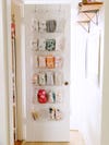 baby clothes hanging in an over the door shoe rack on the door