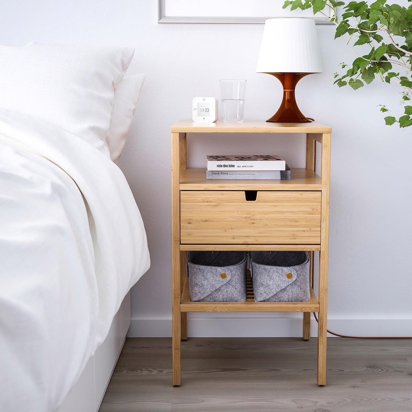 Bamboo nightstand next to white bed