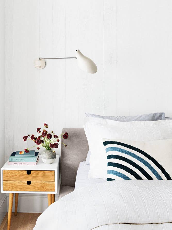 White bedroom with blue striped pillow and wooden nightstand
