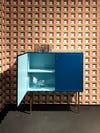 Small blue dresser against an orange patterned wallpaper