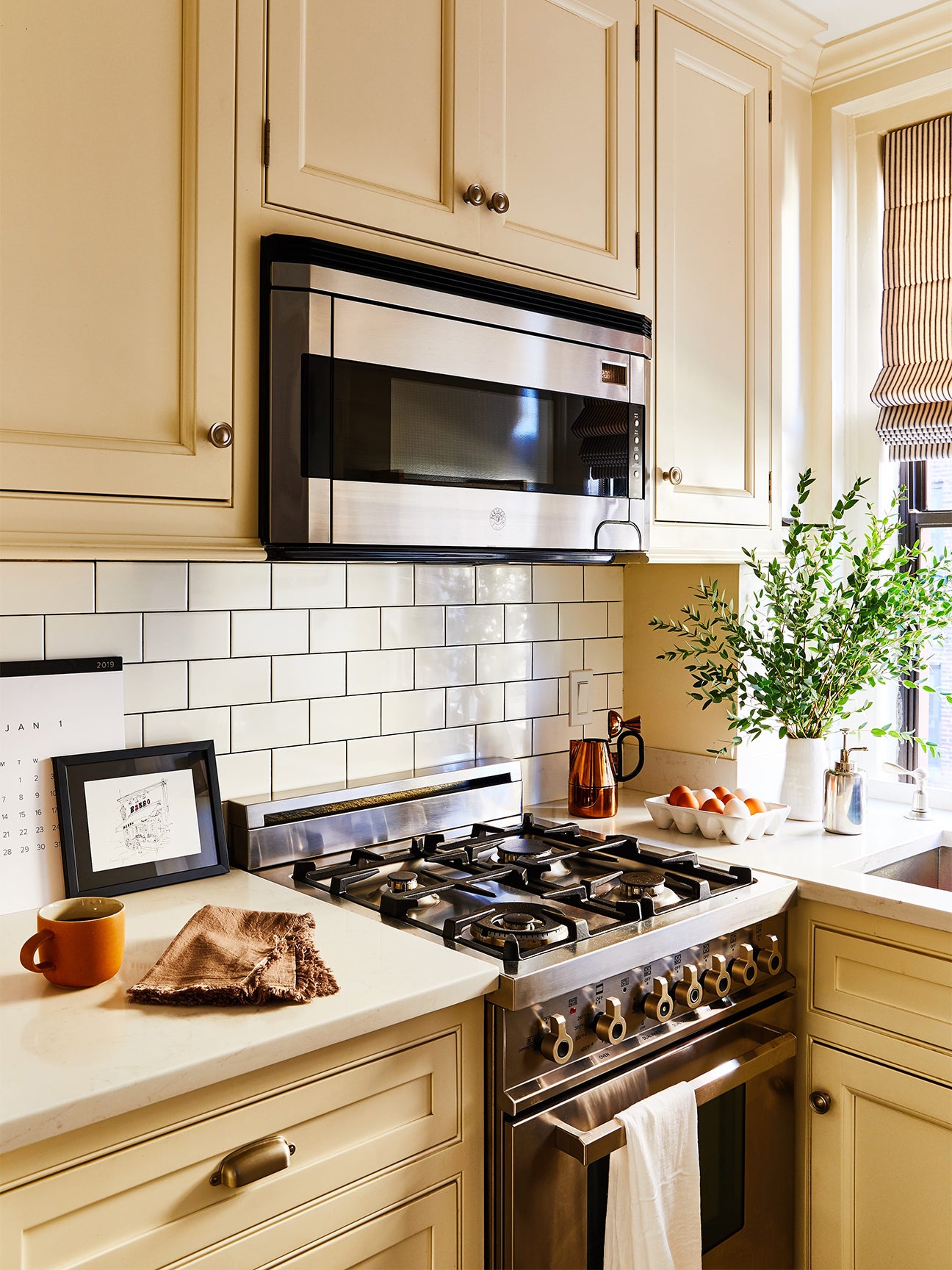 NYC galley kitchen with butter yellow cabinets and subway tile backsplash