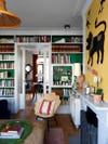 Living room with green bookcases and yellow art