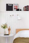 white bedroom wall with low wood bedframe