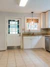 white farm door with white cabinets and dated tan floors