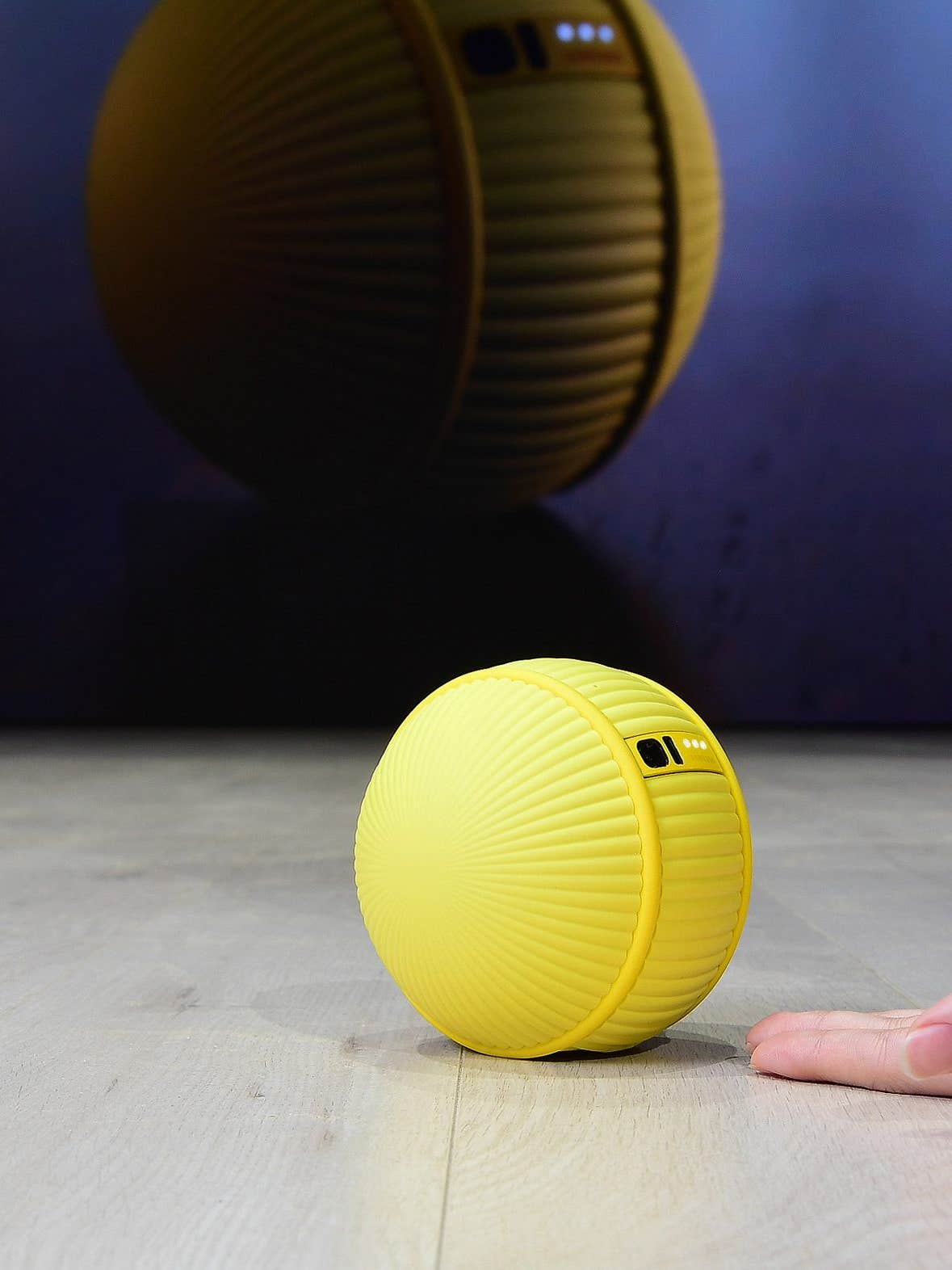 yellow ball on the ground rolling into a human's hand
