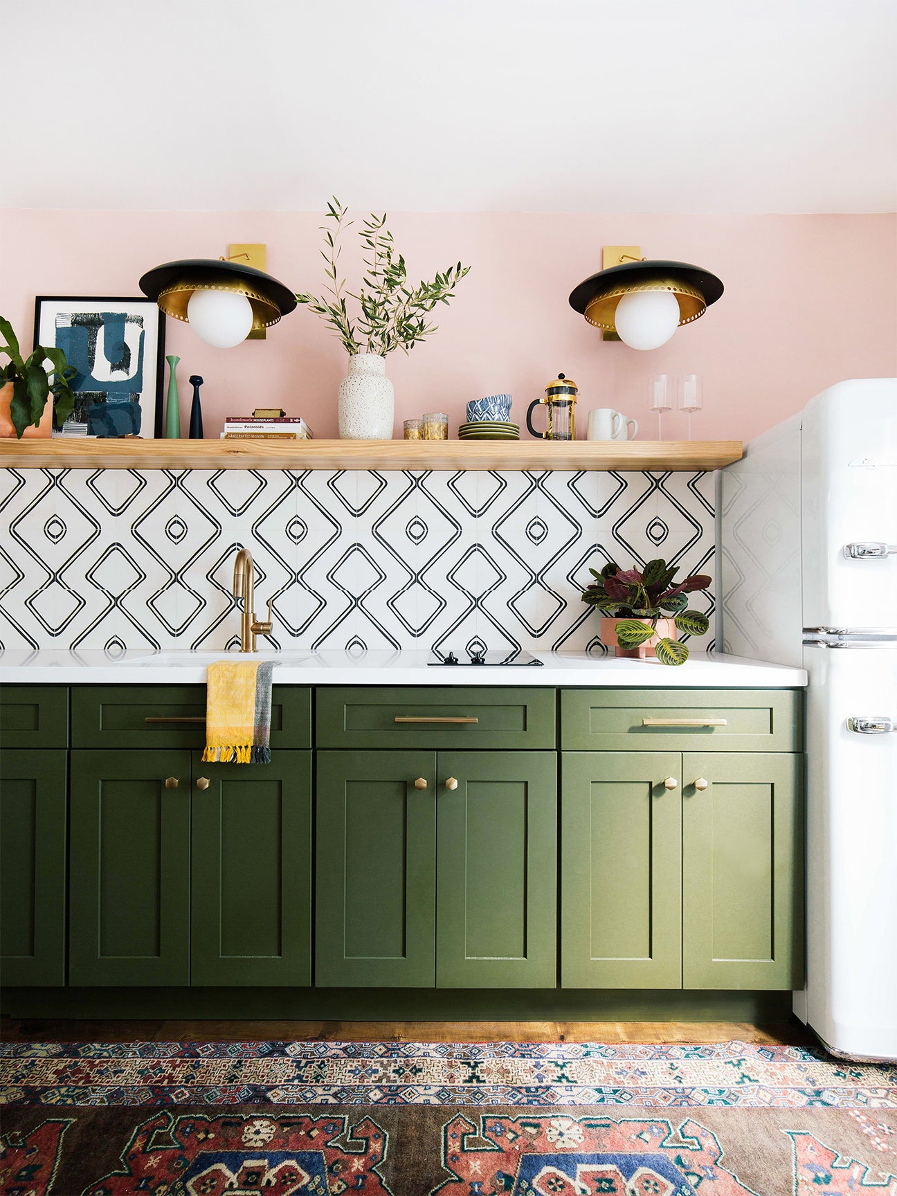 green kitchen cabinets with pink walls and black and white tile backs[lash