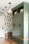 Entryway with leaf-print wall and green cabinet