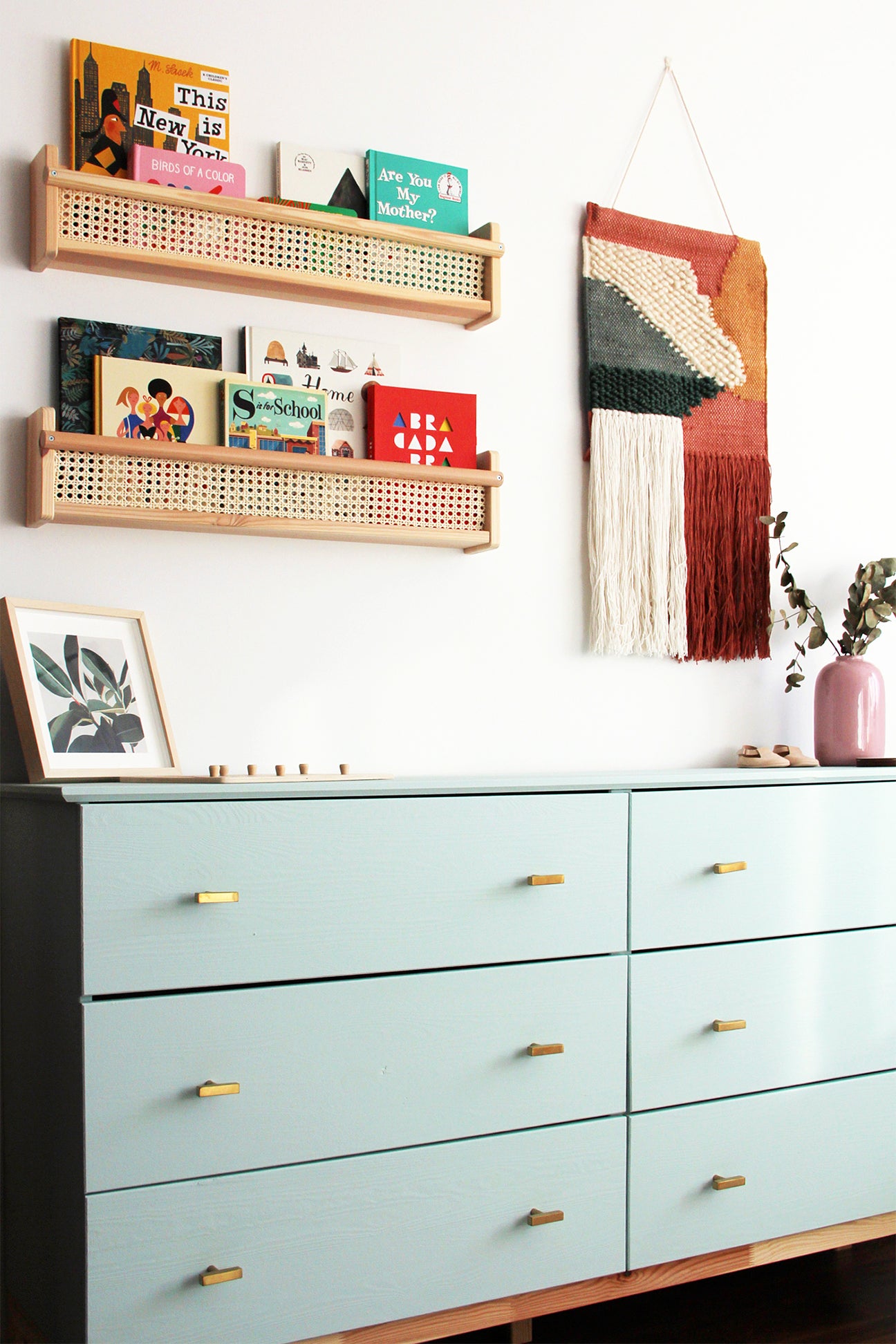 blue six drawer dresser with shelves and art above