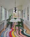 rainbow rug and dining table on it with green chairs