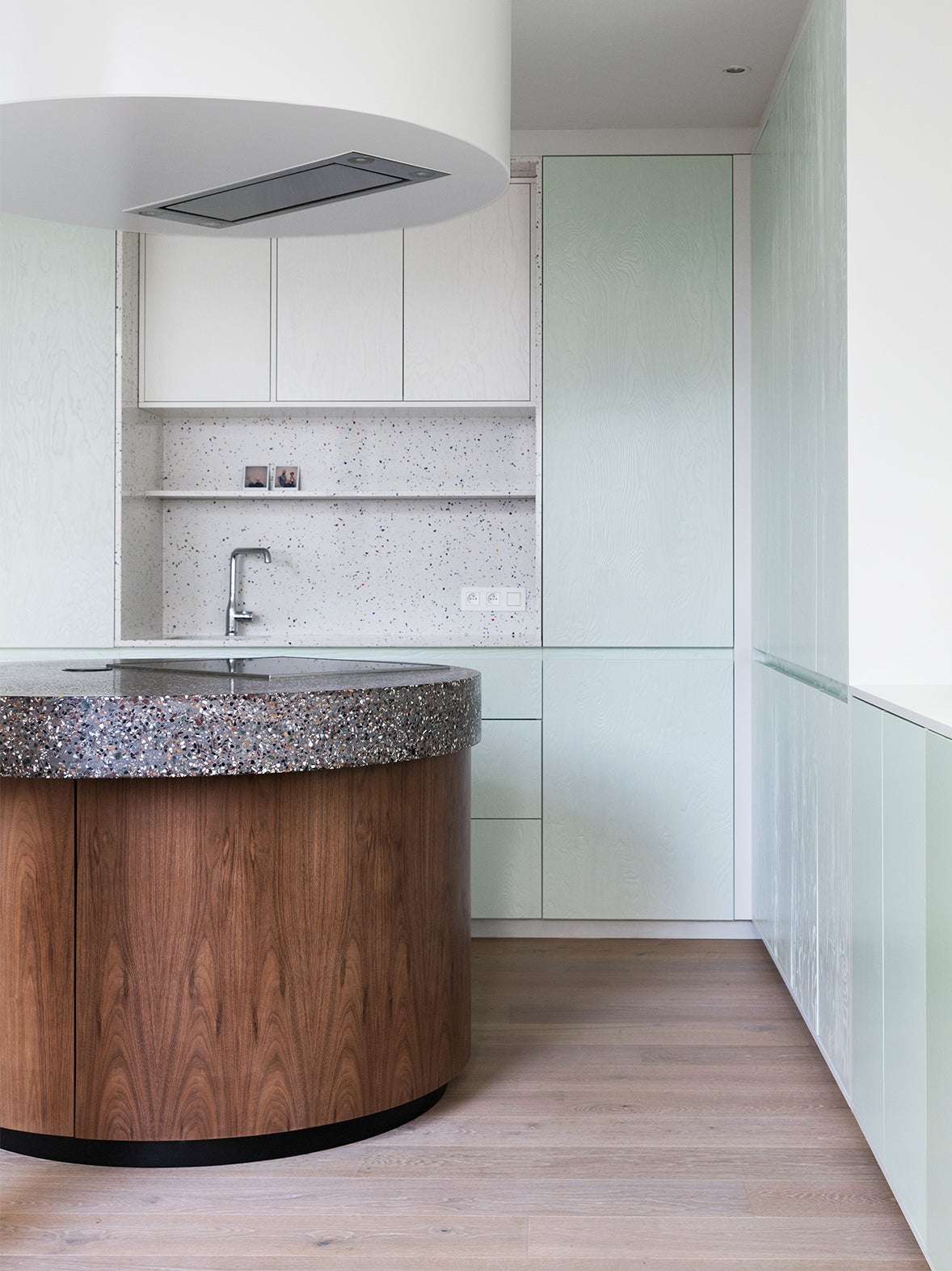 circular terrazzo island withe blue kitchen cabinets
