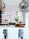 bar stools overlooking kitchen with pink and blue wallpaper wall