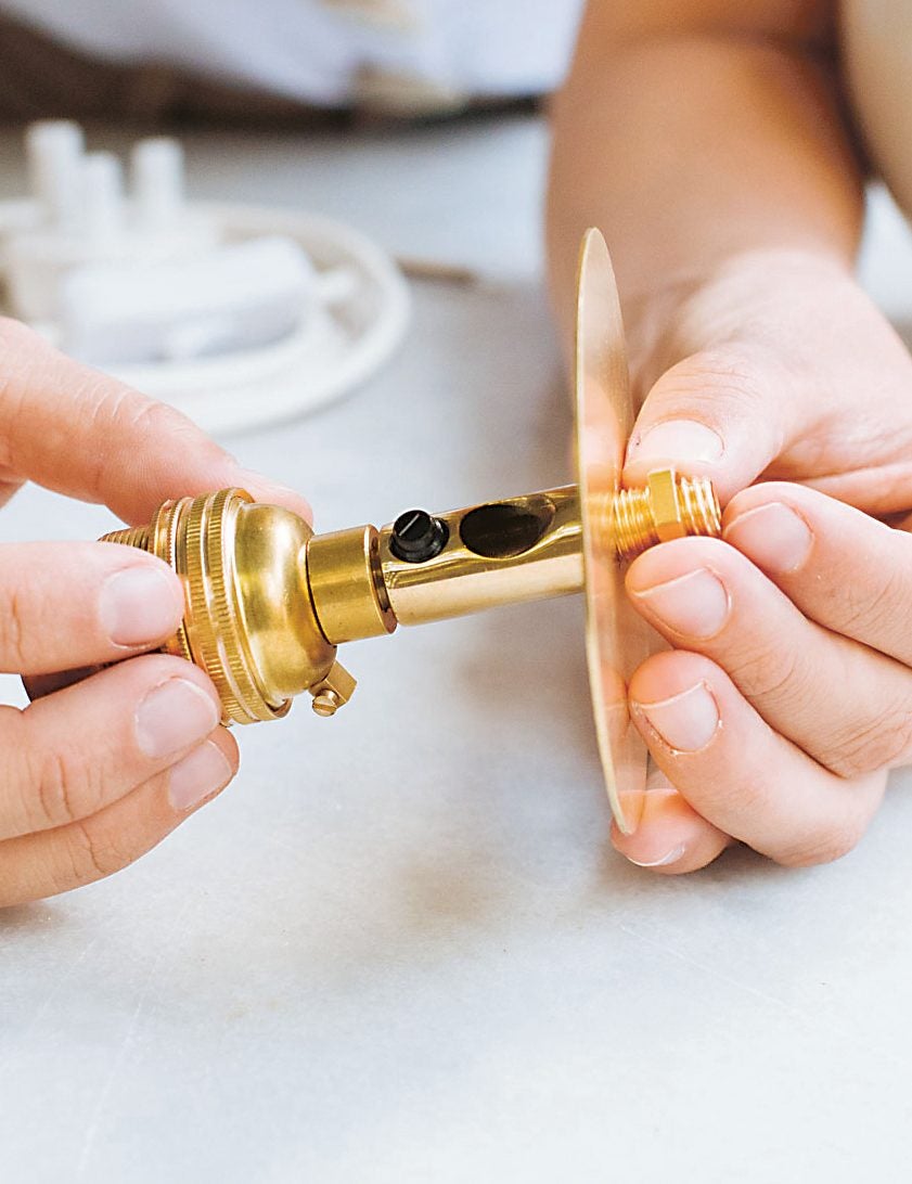 woman screwing two gold parts together