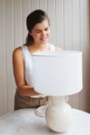 woman putting on a lamp shade