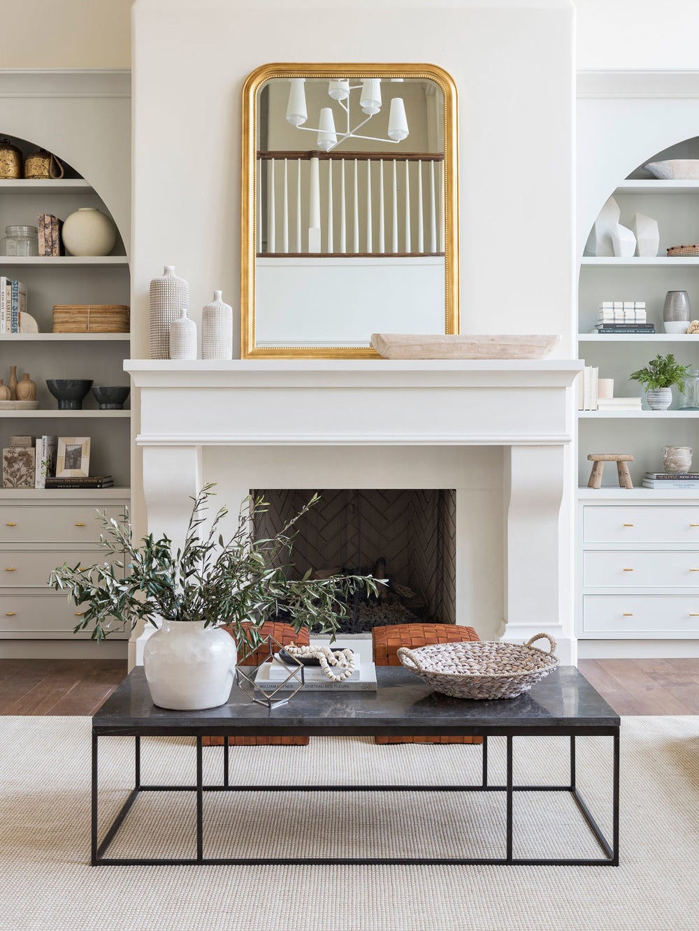 white living room with gold mirror over mantel