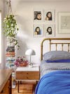 bed with blue sheets, hanging plant, and gallery wall