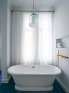 white bathtub in front of curtain window