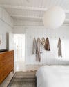 white bedroom with blankets hanging on hooks