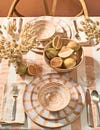 neutral tabletop with ceramic plates and bowls and floral arrangement and fruit