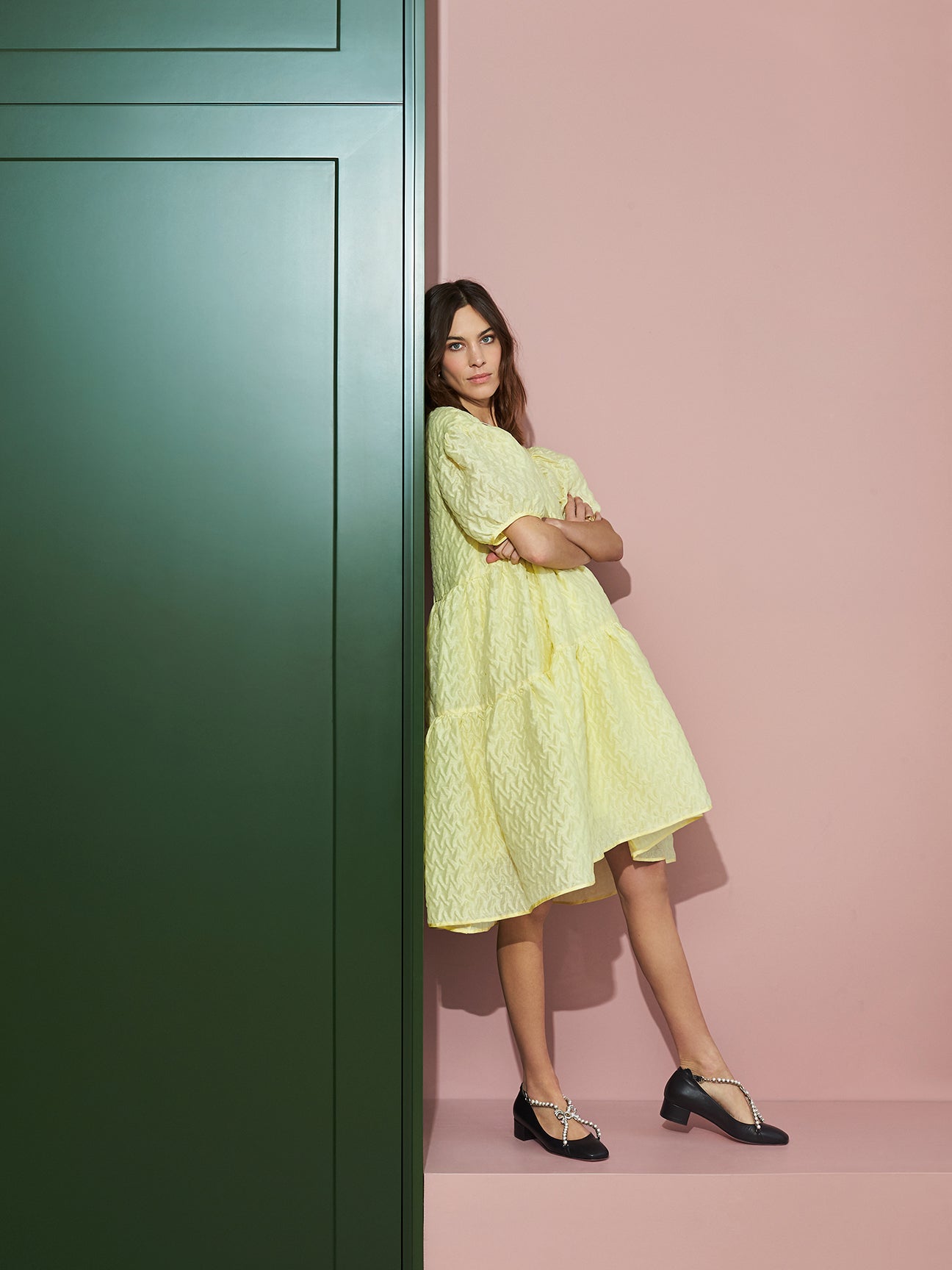 Alexa Chung leaning against a green cabinet