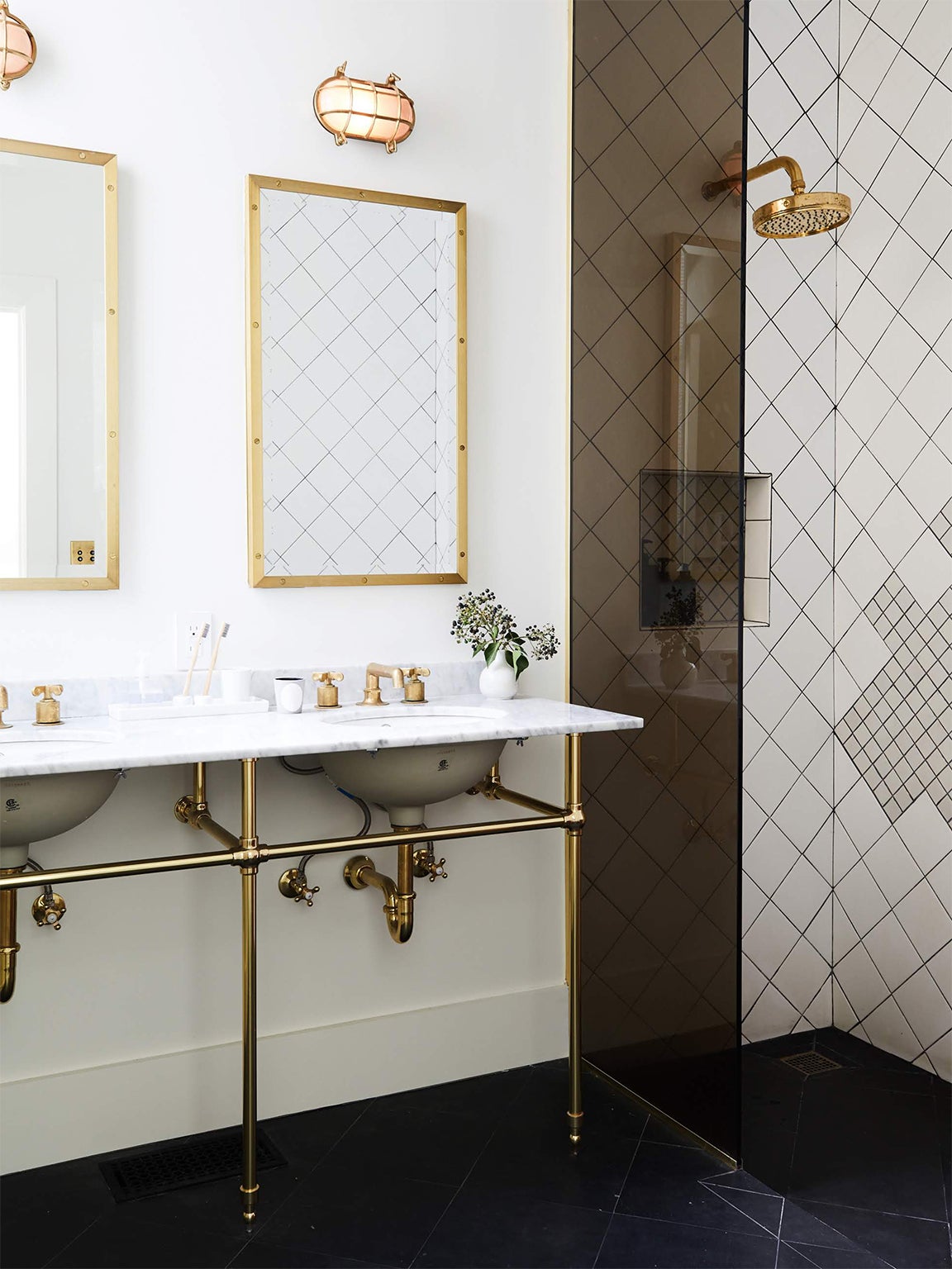 white bathroom with brass fixtures and black glass wall