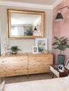 wood dresser with large brass mirror and pink walls