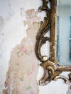 brass mirror with floral wallpaper peeking through