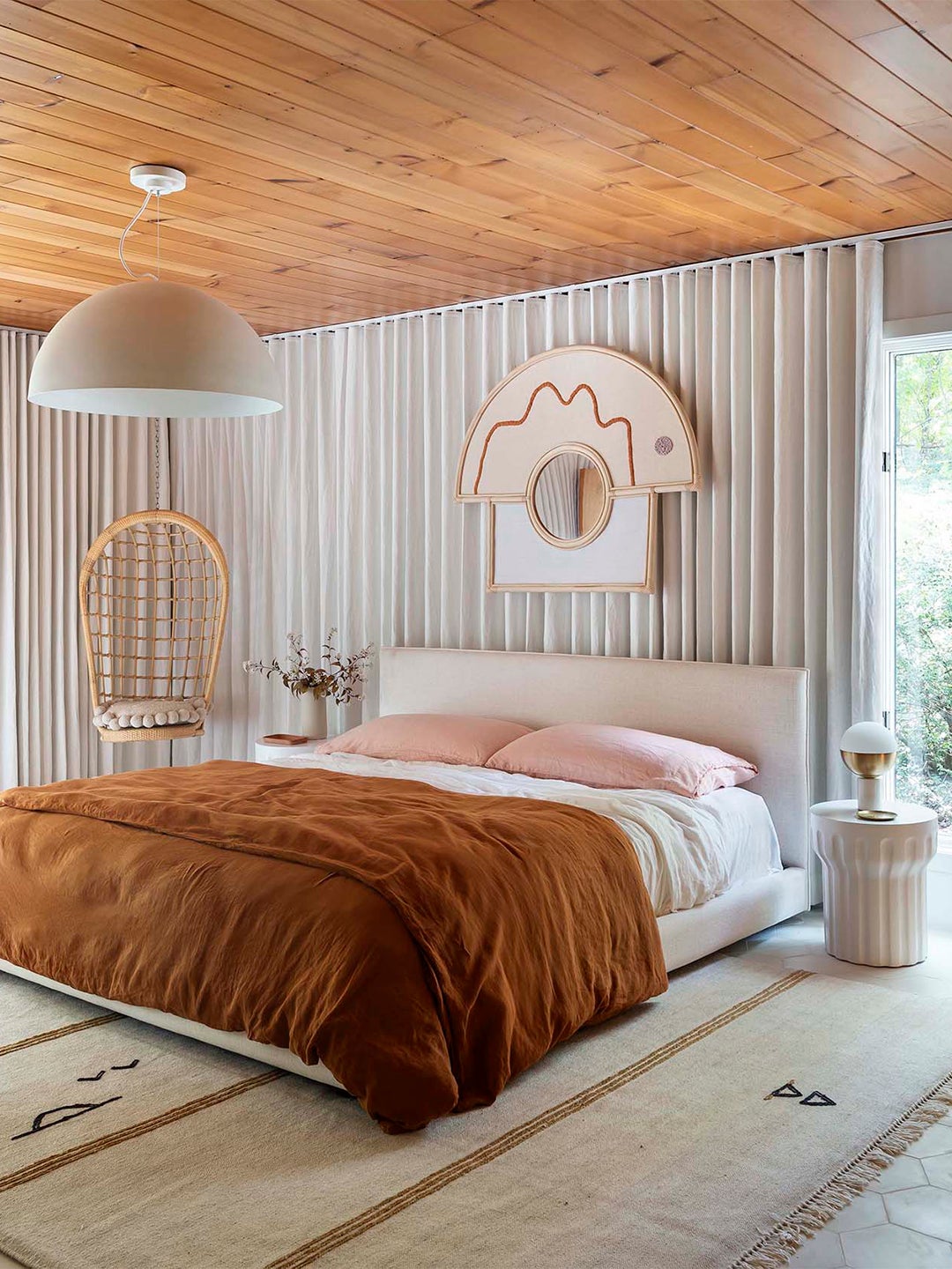 pink and orange bed with modern wood ceiling and gray drapes
