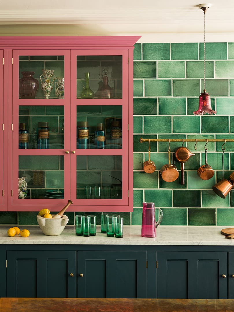 pink glass front kitchen cabinet against green tile backsplash