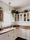 white kitchen with plants on cabinets