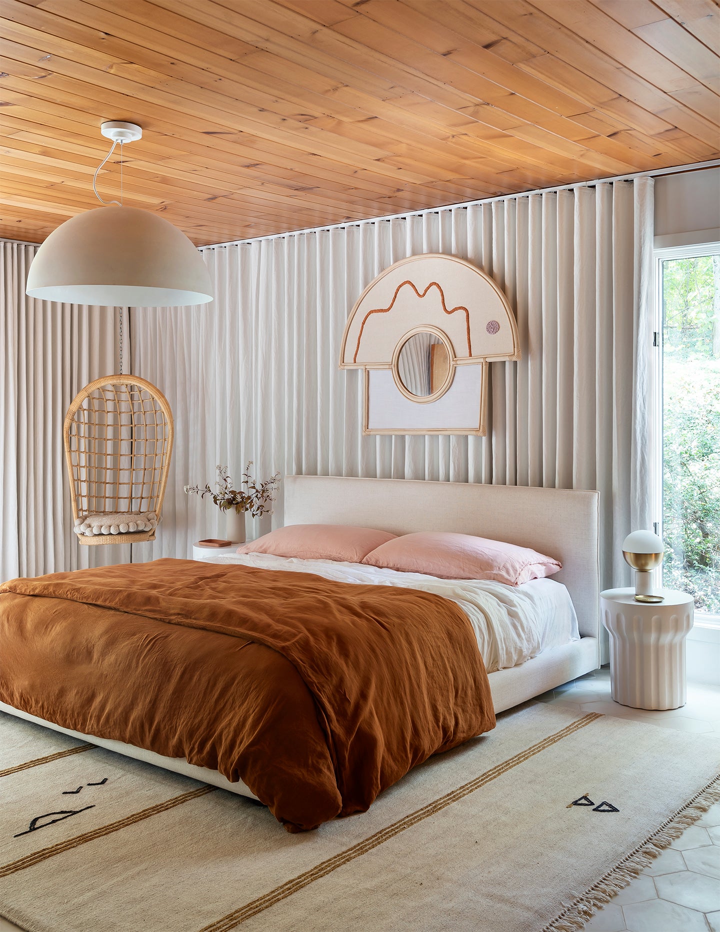 white bedroom with mirror hanging and terracotta bedding