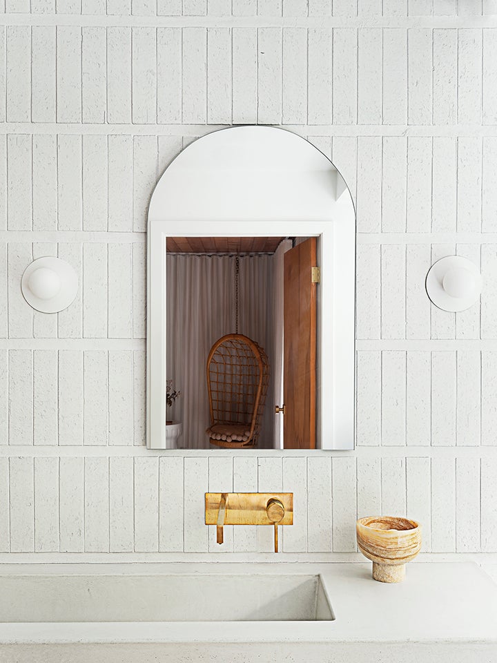 white tile bath vanity with curved mirror and sconces