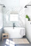 marble bathroom with grey floor tiles and big white tub